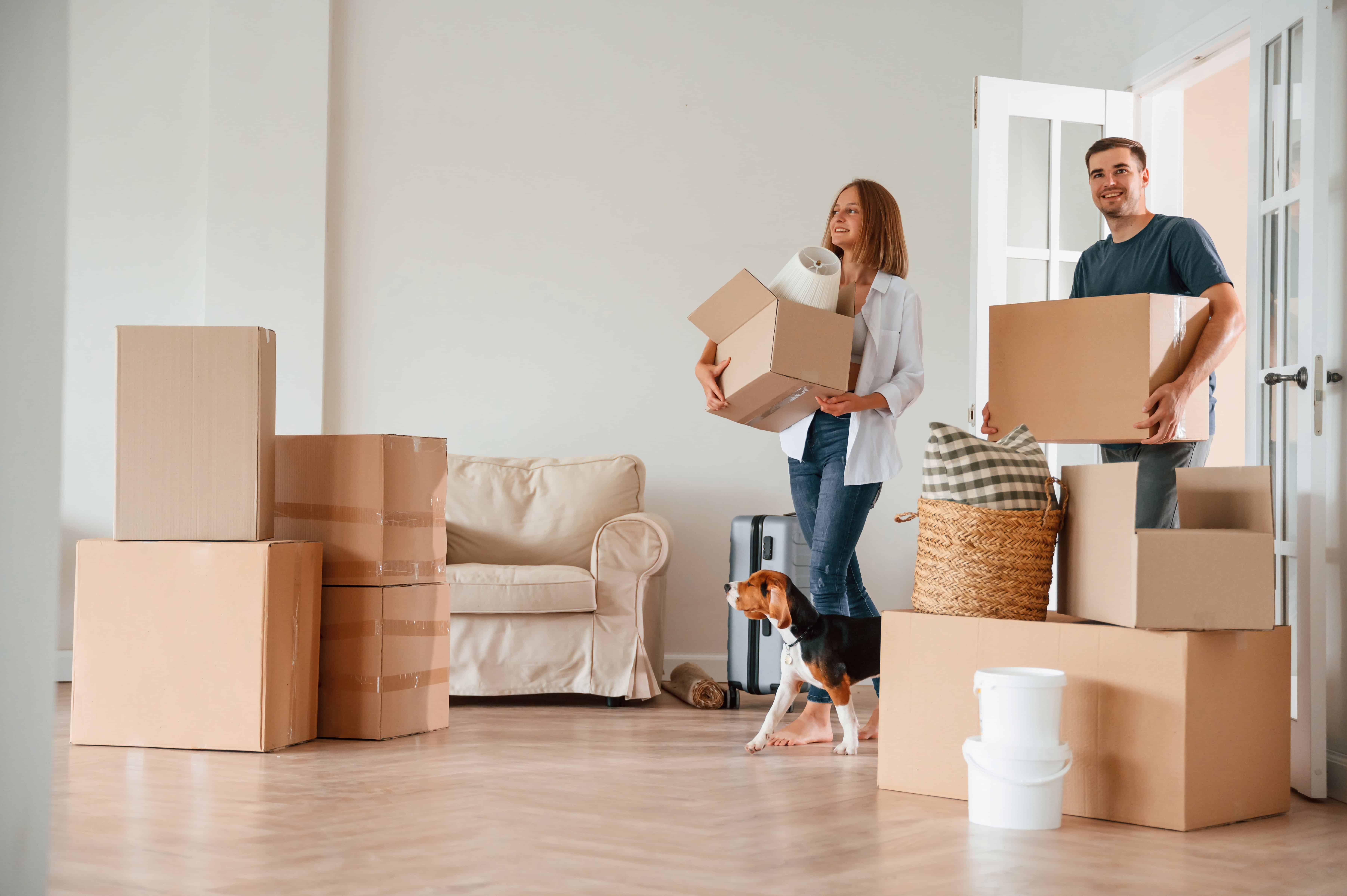 A couple with their dog moving boxes into their new home